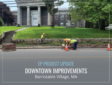 Bricklayers work on a sidewalk in front of a historic building.